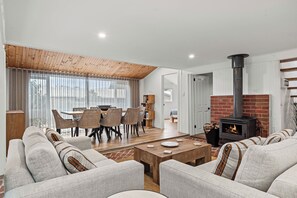 A living room with a sofa set, a dining table, and a fireplace. - Modern Beach holiday House in Rhyll close to Beach, Restaurants, boating (Rhyll)