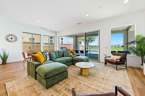 Ein modernes Wohnzimmer mit einem Ecksofa, einem runden Couchtisch und einem Essbereich mit Stühlen.