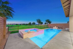 A swimming pool with a hot tub and a fire pit, surrounded by a brick wall and a view of a golf course. - Golf Getaway | Pool, Spa, Arcades, BBQ, PGA West! (La Quinta)
