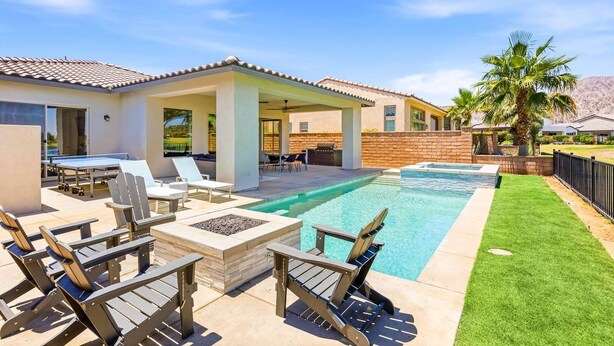 Ein Garten mit Swimmingpool, Sitzgelegenheiten im Freien und einer überdachten Terrasse.