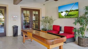 Ein Billardtisch in einem Raum mit Deckenventilator, einem Rauchverbotsschild und einem gerahmten Bild von einem Golfball auf einem Abtee.