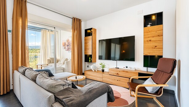 A modern living room with a sofa, a coffee table, a TV, and a wooden cabinet.