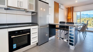 A modern kitchen with a built-in oven, a refrigerator, and a dining area with a view.