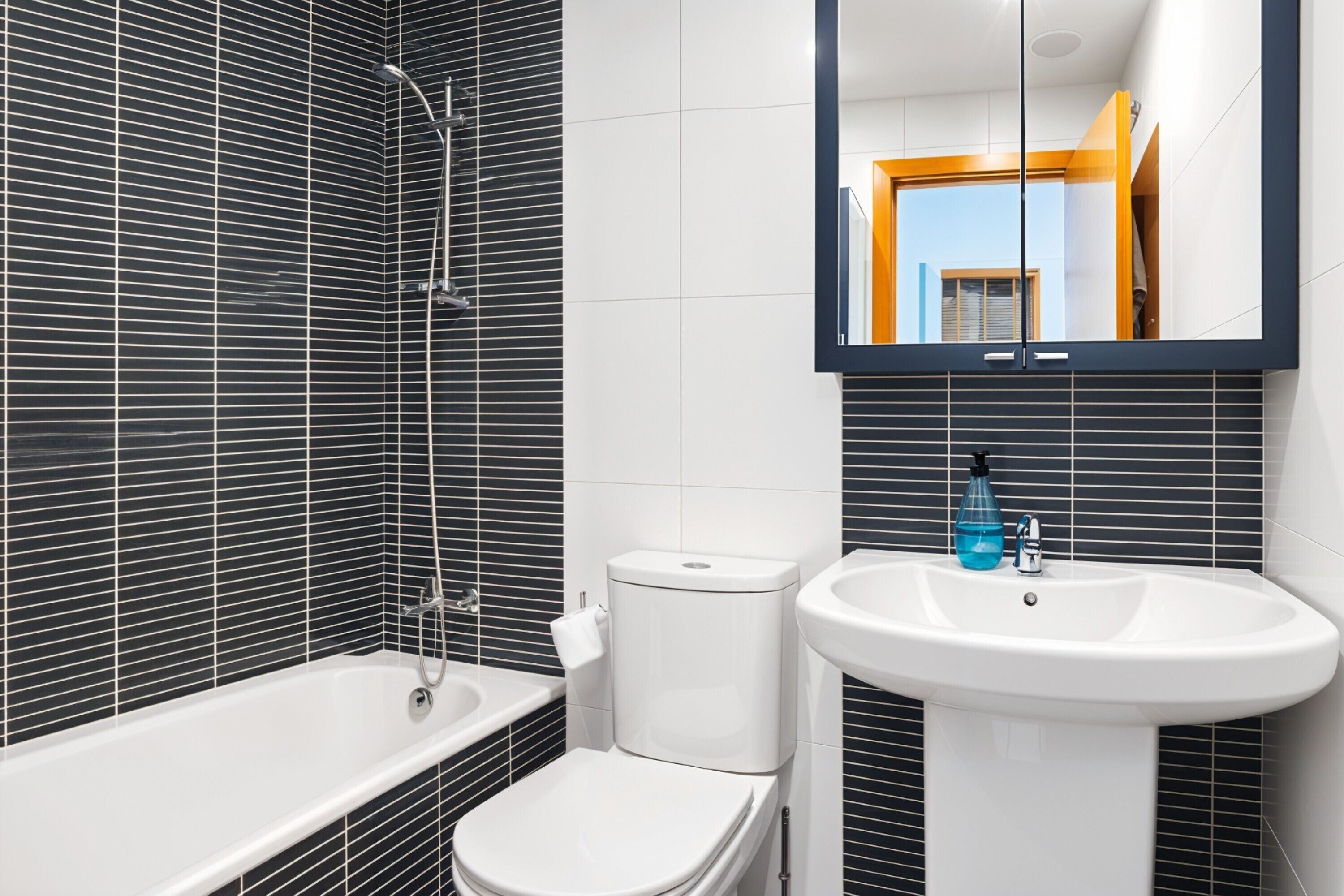 Une salle de bain équipée d’une baignoire, de toilettes et d’un lavabo, avec un miroir au-dessus du lavabo.