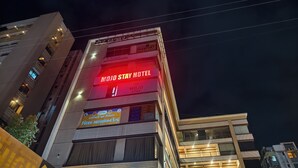 Un hotel con un cartello ben visibile per 'MOJO STAY HOTEL' e un segnale 'Passport' che indica i servizi offerti.