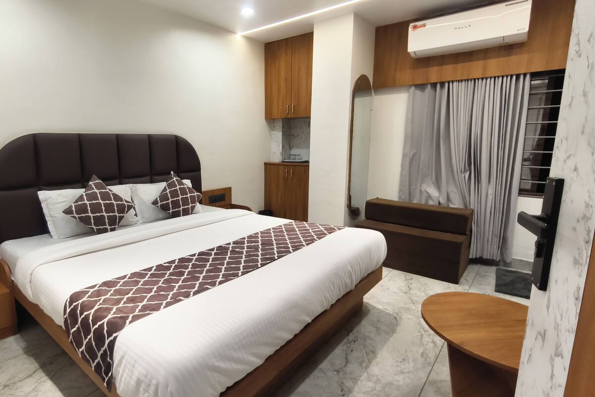 A modern hotel room with a large bed, wooden headboard, and a built-in wardrobe.