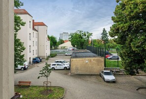 A courtyard with parked cars, a small tree, and a bench. - RentPlanet - Apartament Bukowska (Poznań)