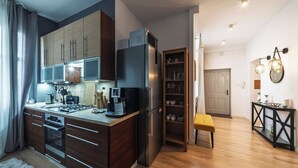 Una cocina moderna equipada con horno, microondas y refrigerador. Hay una zona de comedor con banco y mesa.