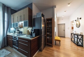 A modern kitchen with a built-in oven, microwave, and refrigerator. There is a dining area with a bench and a table. - RentPlanet - Apartament Bukowska (Poznań)