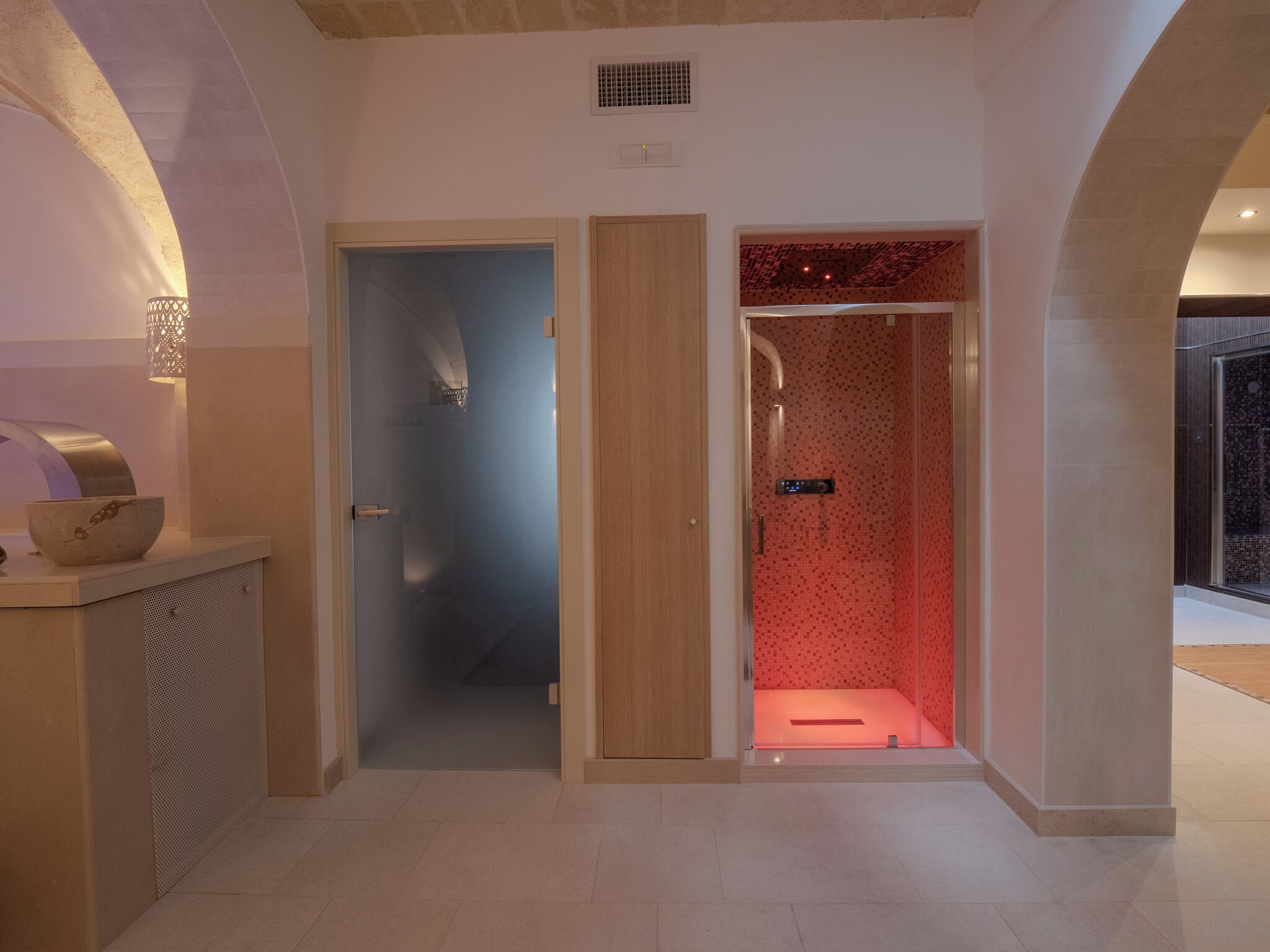 Une salle de bain moderne avec une douche à parois de verre, un meuble-lavabo en bois et un panneau de commande de douche visible.
