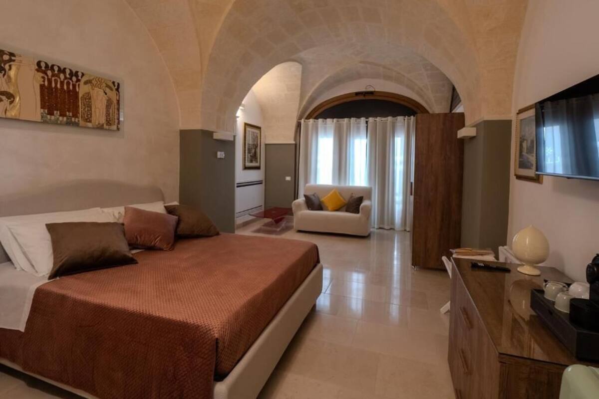 A spacious bedroom with a large bed, a desk, and a sofa.