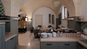 Cocina amplia con comedor, estantes para vino y techo de piedra.