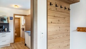 Een moderne keuken met een magnetron, koffiezetapparaat en een wand van houten panelen.