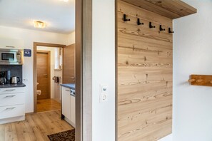 Eine moderne Küche mit Mikrowelle, Kaffeemaschine und Wandverkleidung aus Holz.