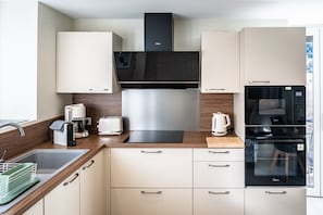 Eine moderne Küche mit Dunstabzugshaube aus Edelstahl, Backofen und Geschirrspüler.