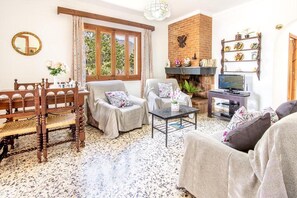 Ein gemütliches Wohnzimmer mit Kamin, Esstisch und Fernseher.