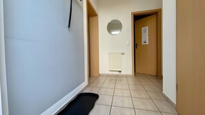Ein Flur mit Heizkörper, schwarzem Teppich, Spiegel und einer Tür mit einem Schild.