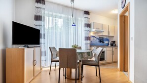 Une cuisine moderne avec un coin repas, des meubles en bois, un téléviseur et une table avec des chaises.