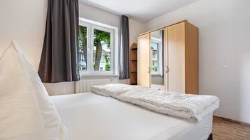 A bedroom with a bed, a wardrobe, a window, and a radiator.