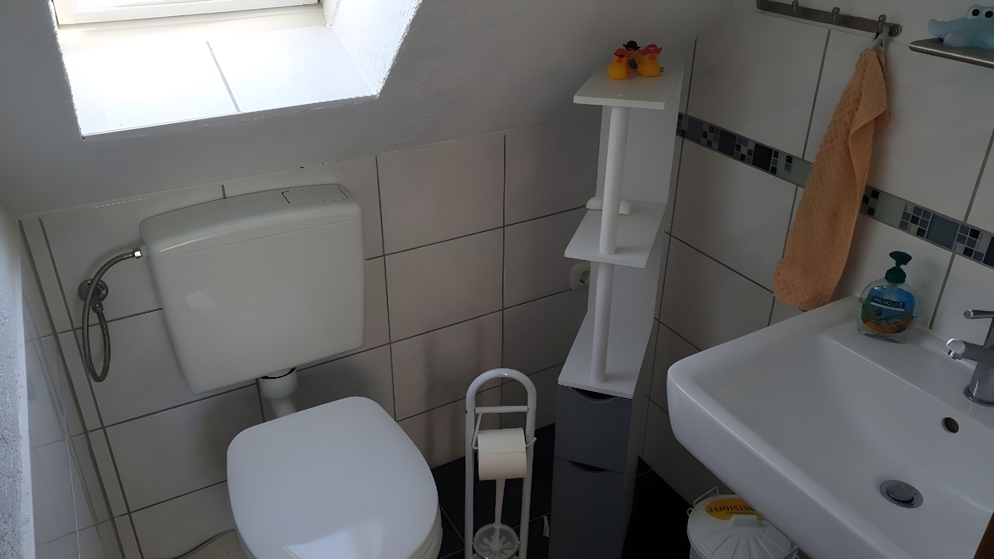 A bathroom with a toilet, a sink, a shower, and a towel rack.