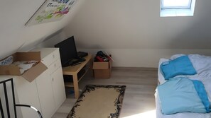 Ein Zimmer mit einem Bett, einem Schreibtisch mit Computer und Kartons.