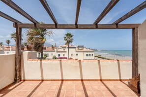 Uma varanda com vista para uma praia, palmeiras e edifícios.
