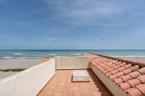 A rooftop terrace with a view of the beach and ocean.