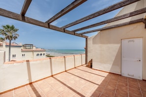 A balcony with a view of the beach, wooden beams, and a white door. - Exclusive Beachfront Villa with Stunning Views and Pool (Marina de Casares)