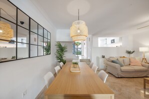 A modern living room with a dining table, white sofas, and a large mirror.