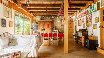 Ein gemütlicher Innenraum mit Holzboden, einem Essbereich mit roter Tischdecke und einer Küche mit Holzschränken sowie einem Schild mit der Aufschrift 'BIERE D'ALSACE'.