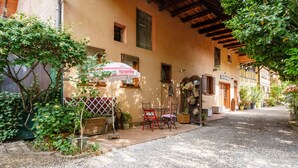 A quaint outdoor seating area with a table and chairs, a wicker basket, and a red umbrella. - Gite Geranium – La Cour de J'Anne in the Heart of Old Schiltigheim (Schiltigheim)