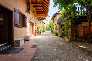 A narrow alleyway with buildings on either side, a gravel path, and potted plants. - Gite Géranium - La Cour de J'Anne, Schiltigheim Centre, Parking, 4 Guests, 2 Bedrooms (Schiltigheim)