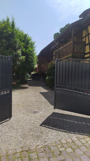 Ein Innenhof mit einem Kiesweg, einem Holzgebäude und einem Metallgitter.