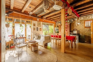 A cozy room with a wooden ceiling, a dining area with a red tablecloth, and a kitchen area. - Gite Géranium - La Cour de J'Anne, Schiltigheim Centre, Parking, 4 Guests, 2 Bedrooms (Schiltigheim)