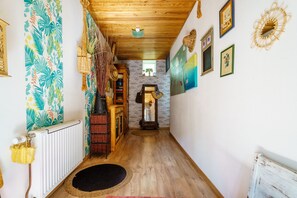 A hallway with a wooden ceiling, a radiator, a wooden cabinet, and a mirror.