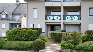 Ein mehrgeschossiges Wohngebäude mit Balkonen, einem Hauseingang und einem gepflegten Garten.