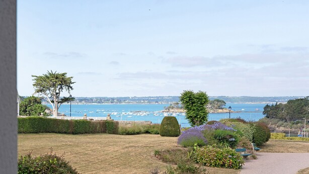 Blick auf die Küste mit einem Weg, viel Grün und einem Marina im Hintergrund.