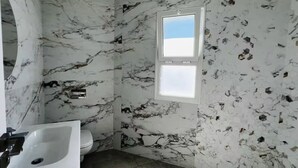 A bathroom with a marble wall, a sink, and a toilet. - Maisons Jassim (Essouani)