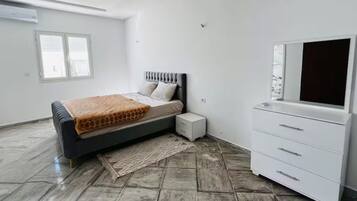 Ein Schlafzimmer mit Bett, Nachttisch, Kommode und Fenster.