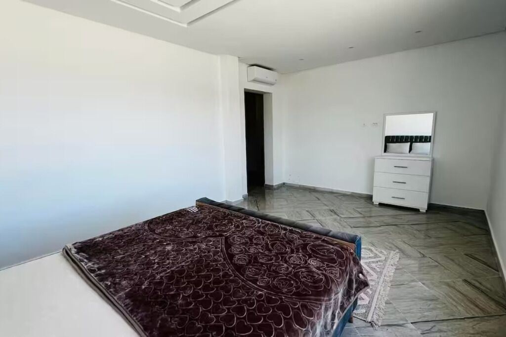 Un dormitorio con cama, cómoda, espejo y puerta que da a otra habitación.