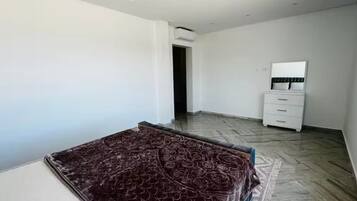 Un dormitorio con cama, cómoda, espejo y puerta que da a otra habitación.