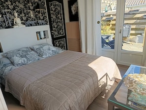 Ein Schlafzimmer mit einem Bett, einem Nachttisch, einem Fenster mit Aussicht und einer Tür.