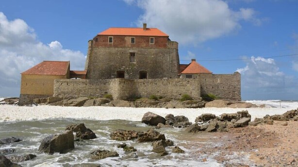 A stone castle with a red roof, situated on a rocky shoreline with waves crashing in the foreground. - Guest Room “La Coccinelle Des Cap - Taupe Zen” with Sea View, Private Terrace & Wi-Fi (Ambleteuse)