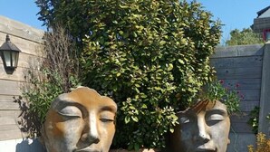 Two large stone sculptures in a garden with a wooden fence and a tree in the background. - Guest Room “La Coccinelle Des Cap - Taupe Zen” with Sea View, Private Terrace & Wi-Fi (Ambleteuse)