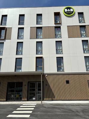 Un moderno edificio de hotel con un llamativo logotipo de B&B, amplios ventanales y una zona de acceso cubierta.