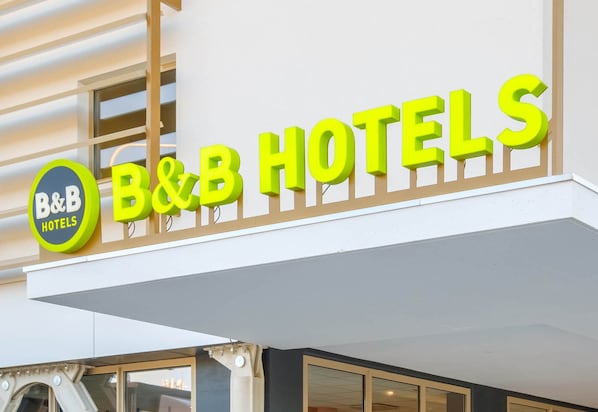 Une enseigne d’hôtel de type « chambre d’hôtes » avec un logo circulaire et le nom de l’établissement écrit en grandes lettres.