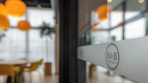 A B&B hotel sign with a modern interior featuring round tables and orange pendant lights.