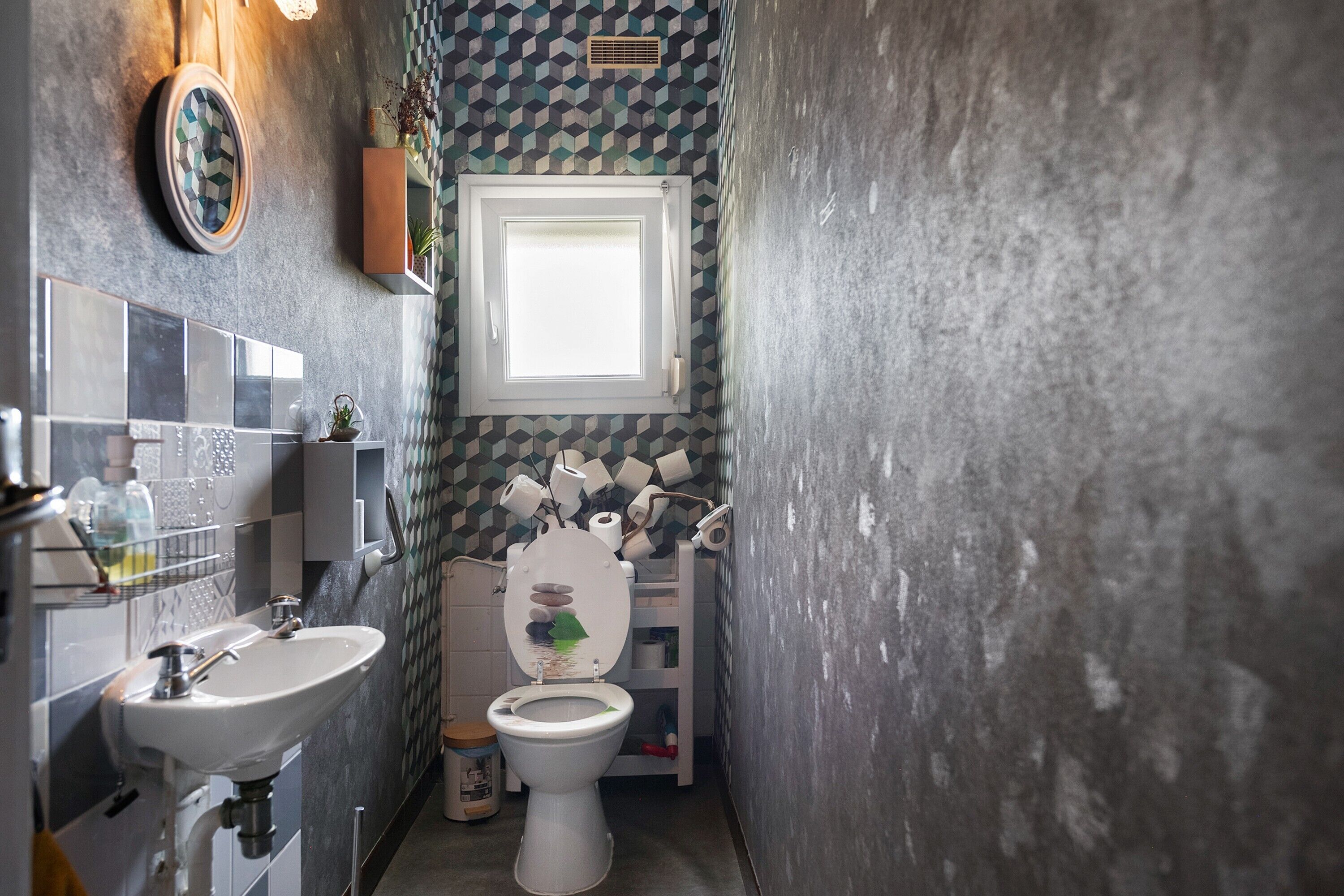 A bathroom with a sink, toilet, and a window.