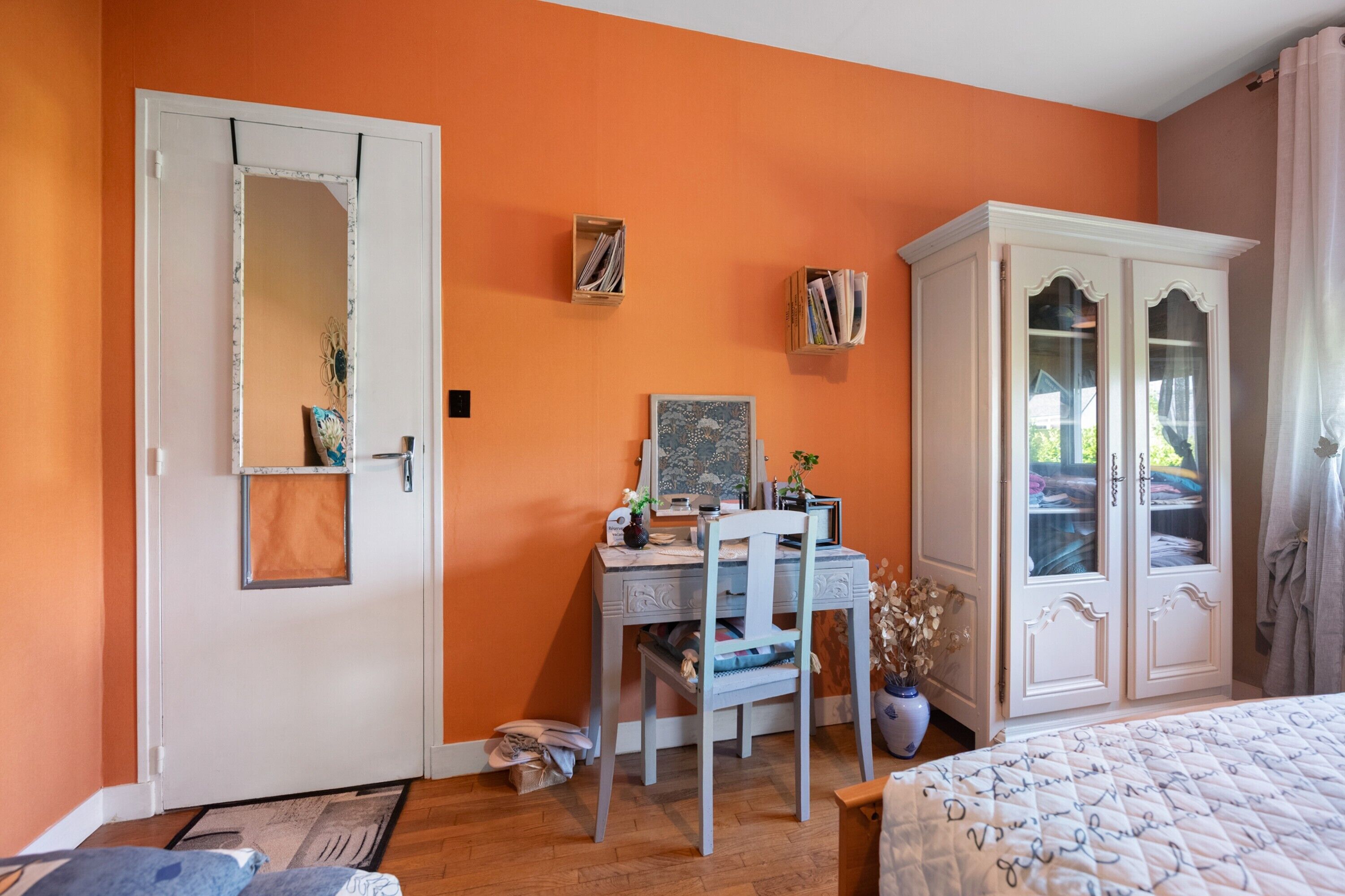 A bedroom with a desk, chair, wardrobe, and a bed.