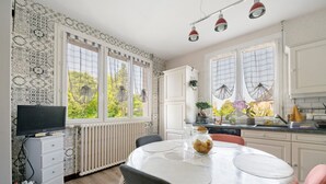 A kitchen with a dining table, white cabinets, and a window with curtains.